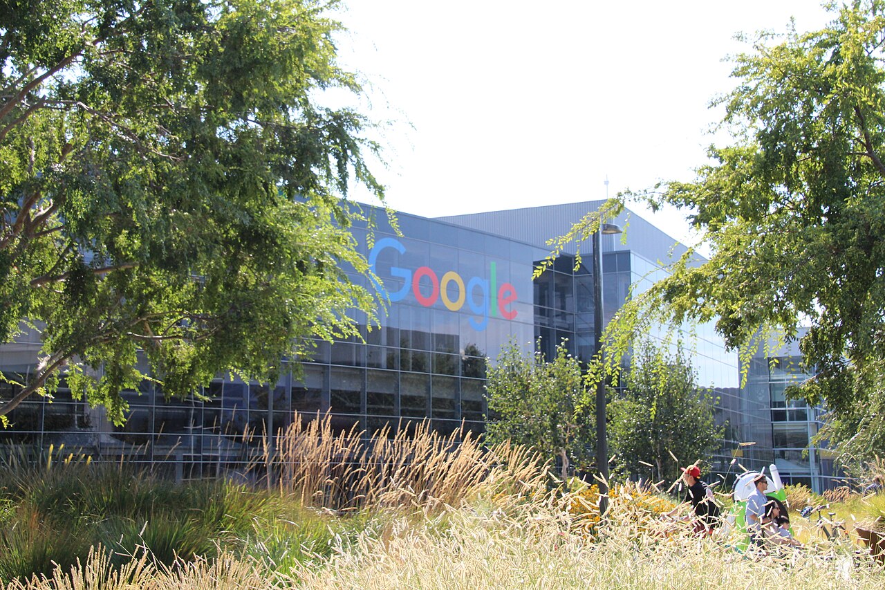 Google's logo on a glass-fronted building at the Googleplex campus in Mountain View, California, seen through trees
